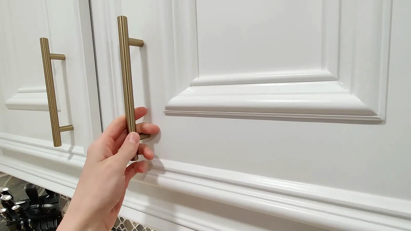 Newly refinished white kitchen cabinets with gold bar pulls.