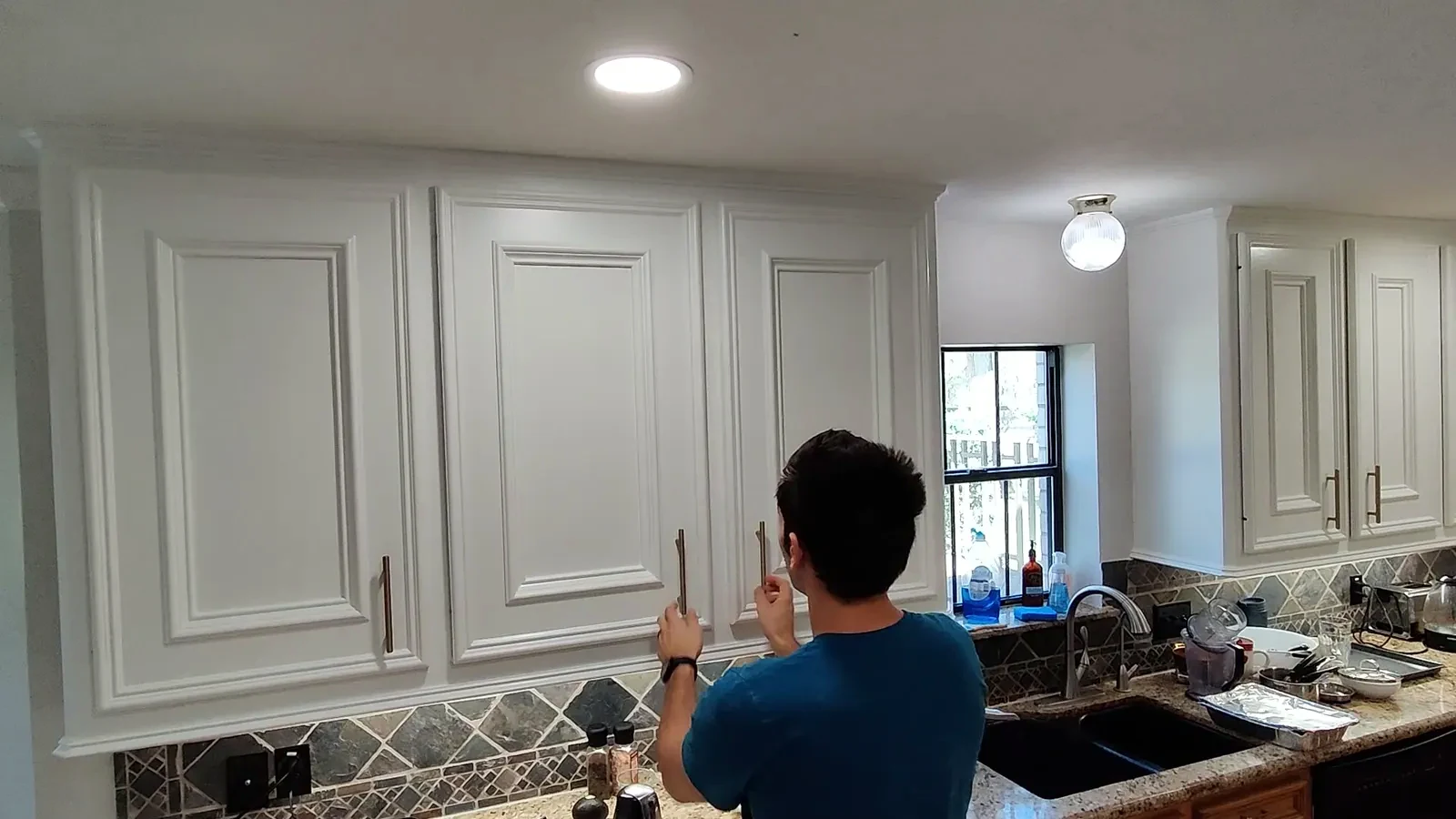 Full view of the kitchen with bright white upper cabinets and new gold hardware.