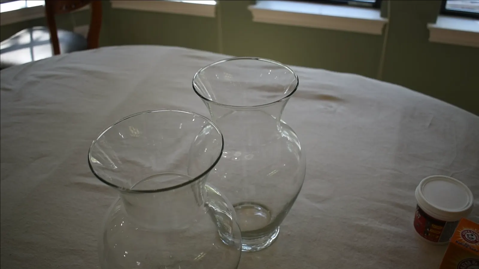 Two clear glass vases on a white surface before any paint is applied.