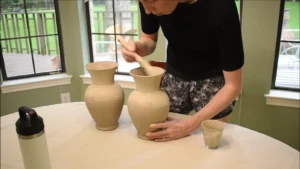 A close-up of the vase after two coats of paint and baking soda, showing a rough, stone-like texture.